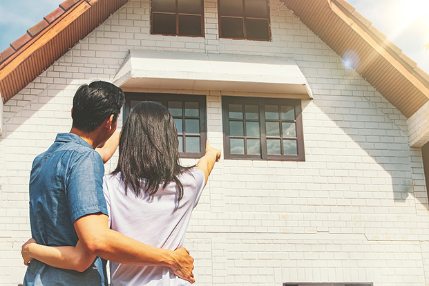 Couple standing outside a new home while preparing for a summer move