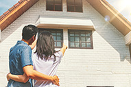 Couple standing outside a new home while preparing for a summer move